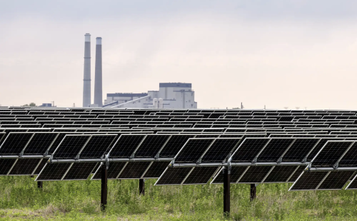A coal-fired plant looms over acres of solar panels at Xcel Energy’s Sherco Solar 1 site in Clear Lake, on May 29
