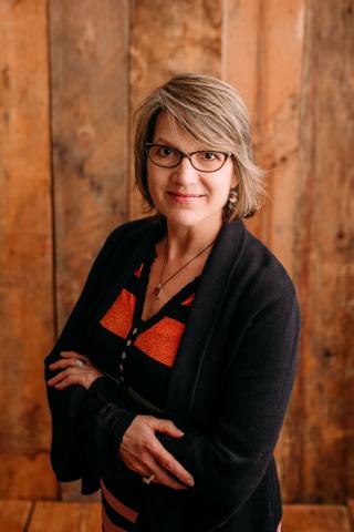 Suzan Klein headshot with wood grain background.