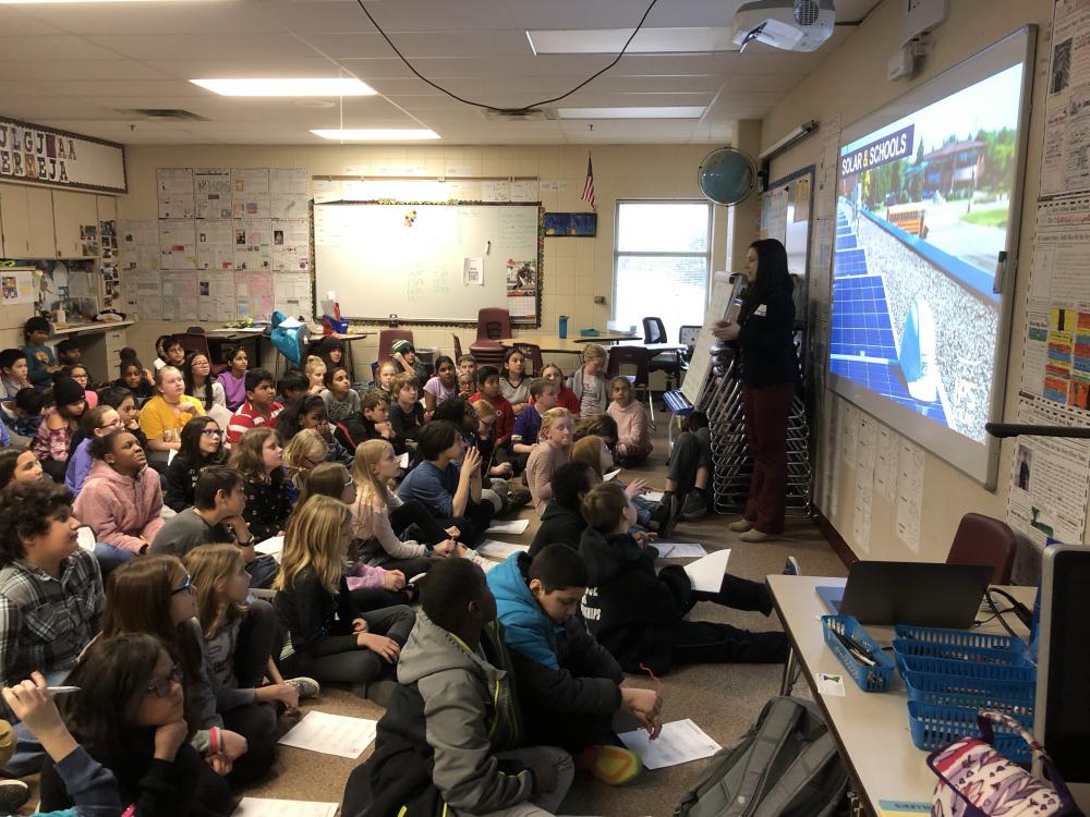 Liz Lucente of MnSEIA in front of 150 5th Graders teaching solar at Glacier Hills Elementary